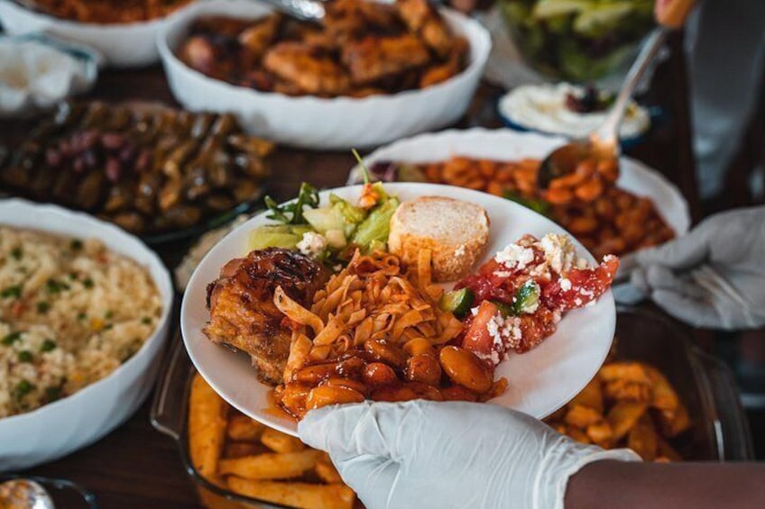 A variety of dishes including a plate with fried chicken, vegetables, and a bun, held by a person wearing a white glove. 3