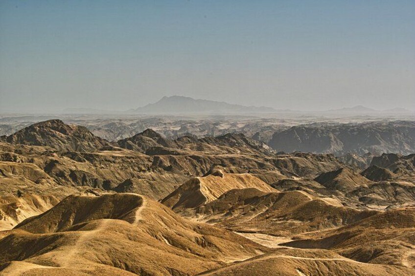A vast desert landscape with rolling hills and distant mountains under a clear sky. 4