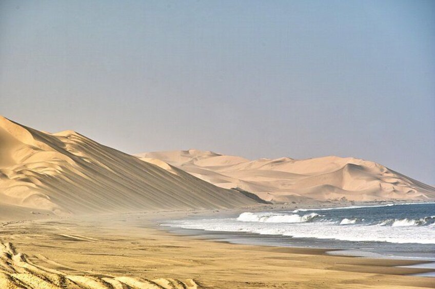 Een woestijnlandschap met zandduinen en een strand. 5