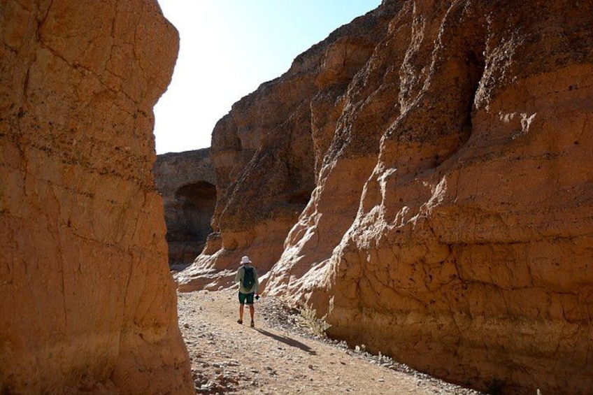 A person hiking through a narrow canyon with rocky walls. 2