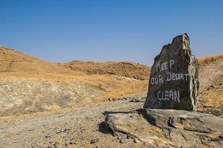 A rock with the inscription 'KEEP OUR DESERT CLEAN' in a desert landscape. 4