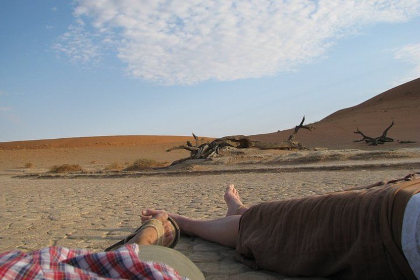 A person lying on the sand with a desert landscape in the background. 2