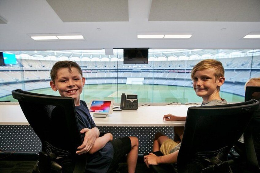 A control room with a large screen displaying a stadium. 2