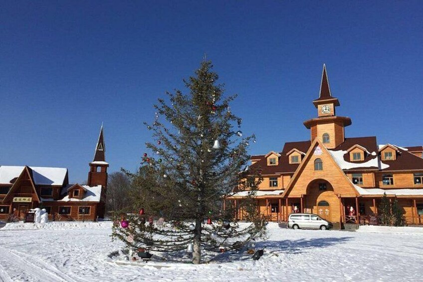 A snow-covered building with a prominent tower and a large tree in front. 2