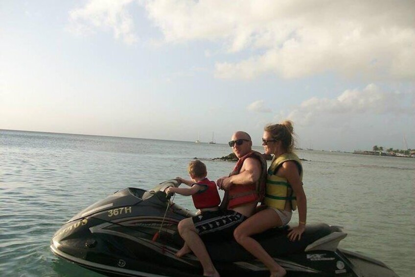 Una familia en un jet ski, con vistas despejadas al océano y barcos a lo lejos. 2