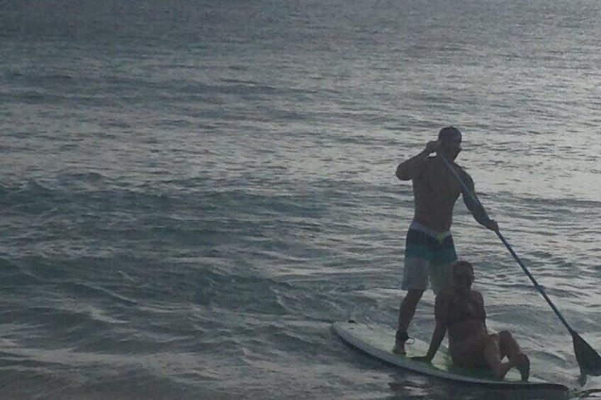 Una persona de pie en una tabla de paddleboard sobre el agua, sosteniendo un remo. 3