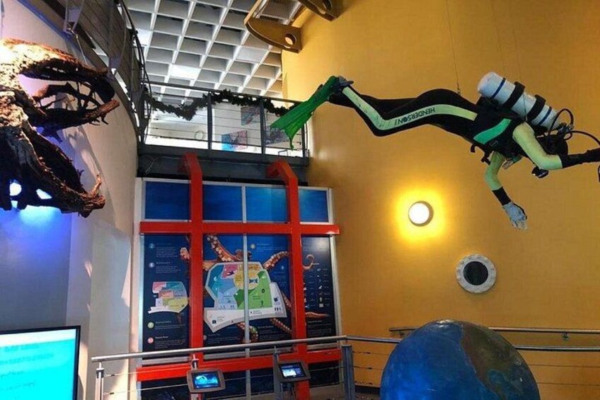 A diver in a green and black suit suspended in mid-air, a large blue globe, and a red and white structure. 2
