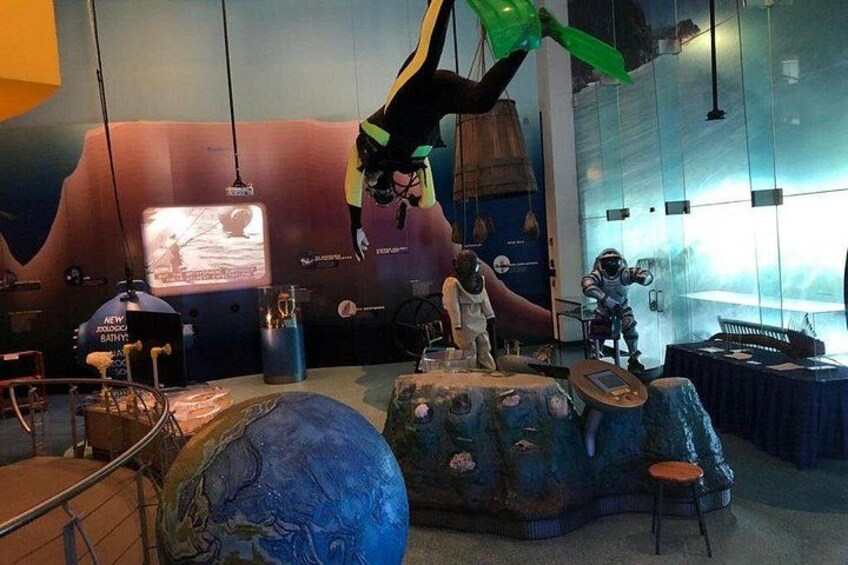En museumsudstilling med astronautfigurer, en stor globe og et projektionslærred. 4