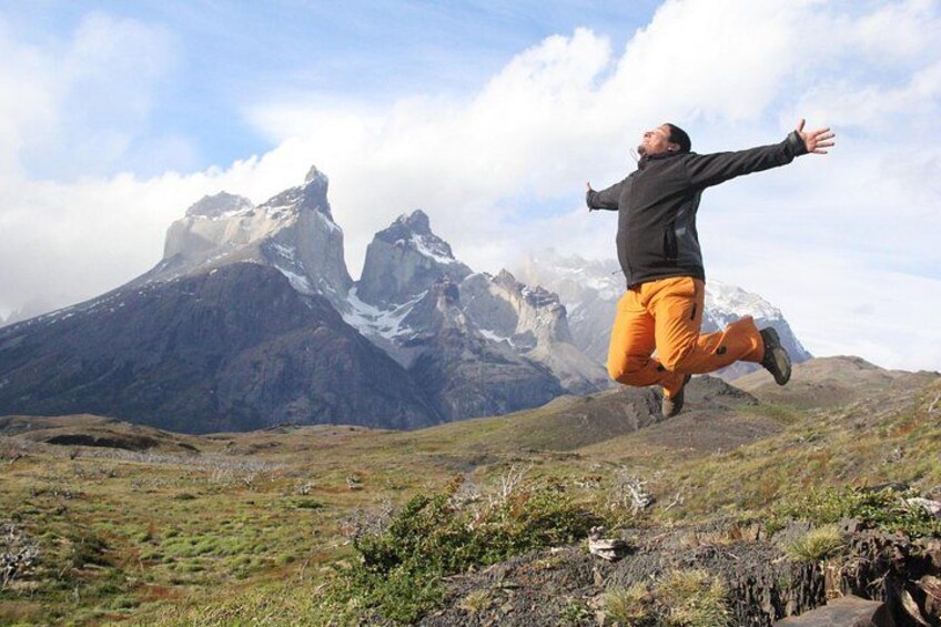 Eine Person springt in einer Berglandschaft, im Hintergrund schneebedeckte Gipfel. 3