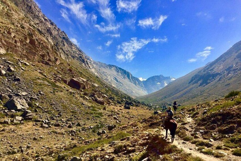 A mountainous trail with hikers, rocky terrain, and a clear sky. 3