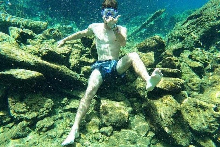 A person snorkeling underwater among rocks. 5