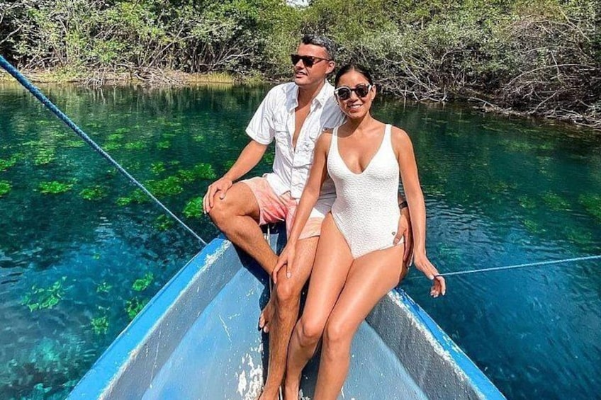 A couple on a boat in a clear blue water body surrounded by greenery. 4