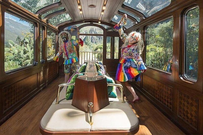 A train interior with a central aisle, wooden paneling, and large windows. 1