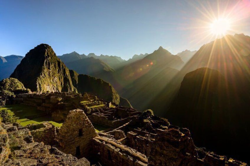 Machu Picchu ruins, a mountain range, and the sun. 5