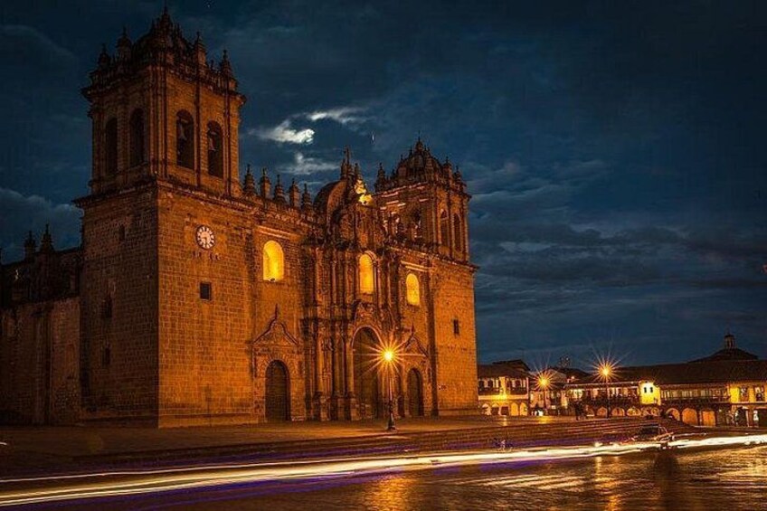 Una cattedrale storica con una torre dell'orologio, illuminata dai lampioni. 5