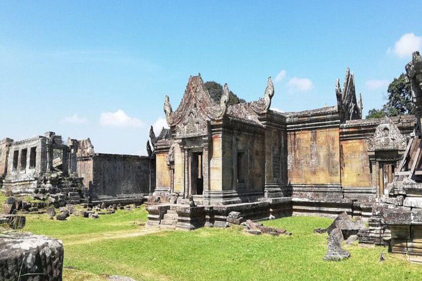 Ancient ruins with stone structures and a grassy area. 1