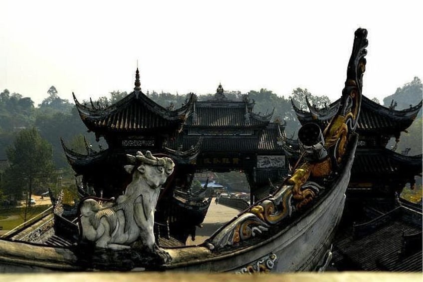A traditional boat with ornate decorations and a statue of a cow, docked at a temple with tiered roofs. 4