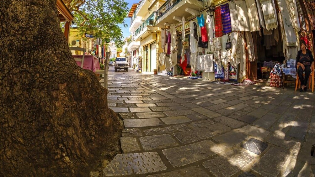 Una calle empedrada bordeada de tiendas que exhiben textiles y telas. 5