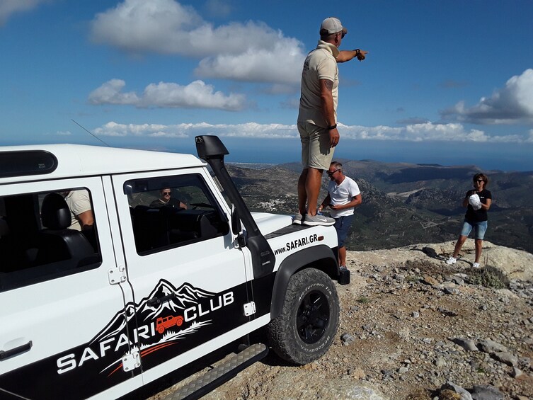 Un vehículo tipo safari blanco estacionado sobre terreno rocoso, con un paisaje montañoso al fondo. 2