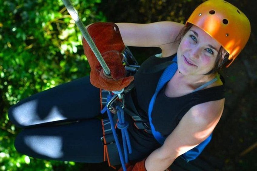 A person wearing a helmet and harness, suspended in a zip line. 2