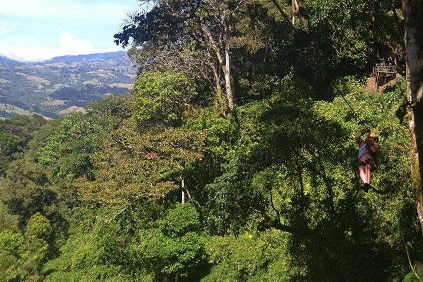 A person rappelling down a cliff surrounded by dense green forest. 3