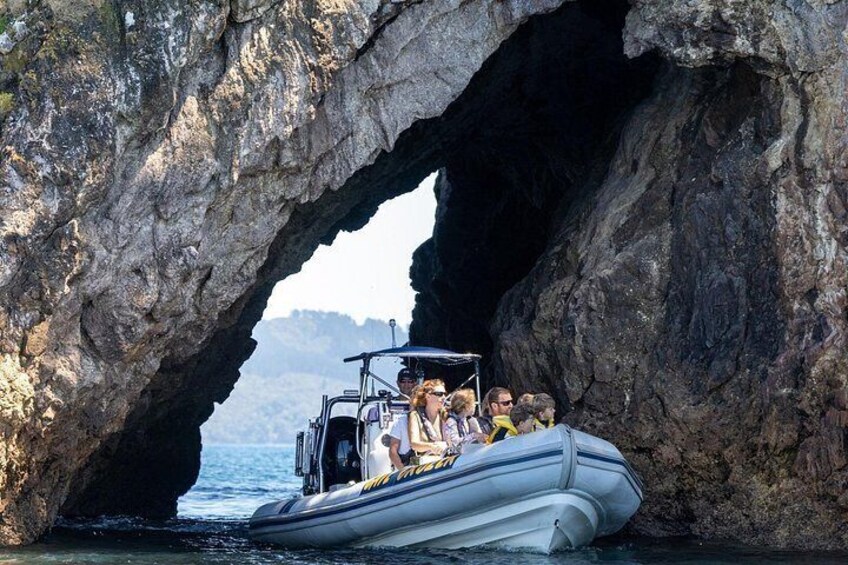 Un bateau transportant des passagers traverse une formation rocheuse en forme d’arche. 1