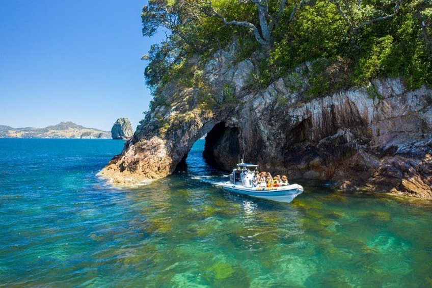 Un bateau près d’une côte rocheuse, avec une eau claire et une formation géologique ressemblant à une grotte. 4
