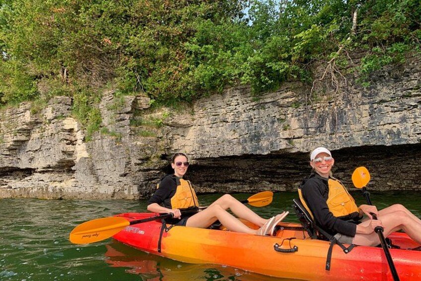 Dos personas en kayak por un río con acantilados rocosos al fondo. 3