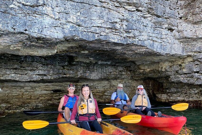 Cuatro personas kayakendo en un río tranquilo con acantilados rocosos al fondo. 5