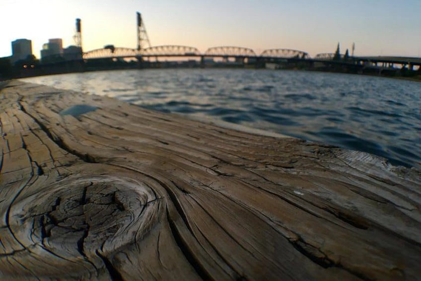A wooden dock with a river and a bridge in the background. 2