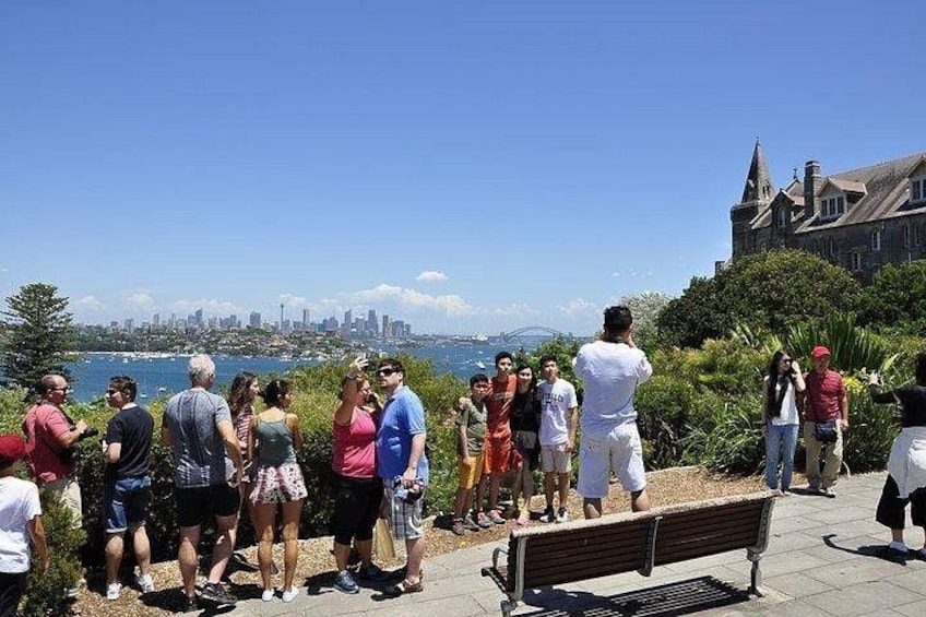 Un groupe de personnes se tient sur une promenade en bord de mer, d’où l’on peut admirer la vue sur les gratte-ciel d’une ville. 2