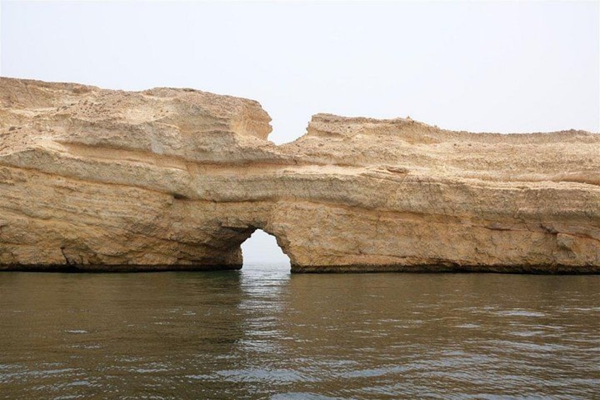 A natural rock formation with a large arch over water. 2