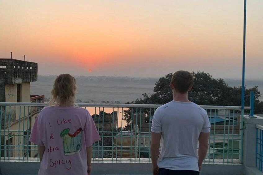 Two people standing on a balcony overlooking a sunset. 3
