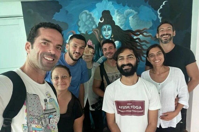 A group of people posing in front of a mural with a figure in the background. 3