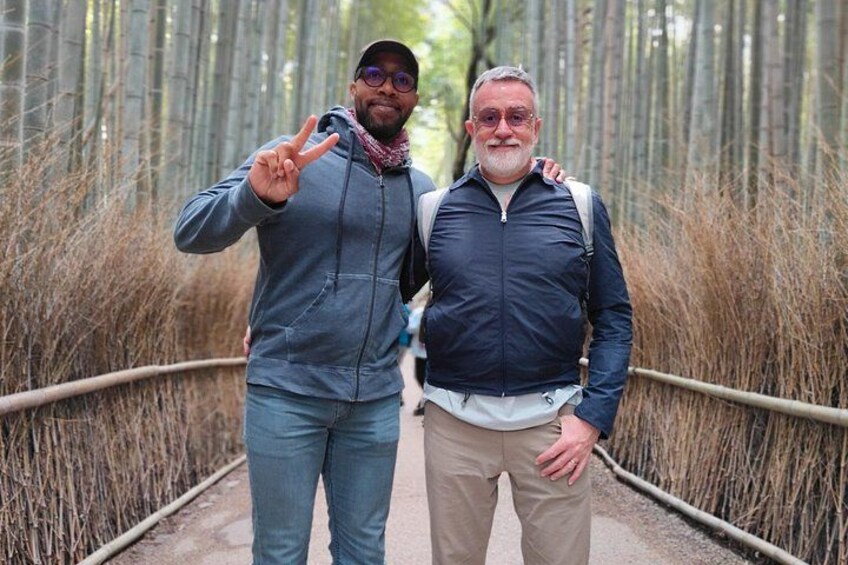 Two people standing on a bridge with bamboo on either side. 4
