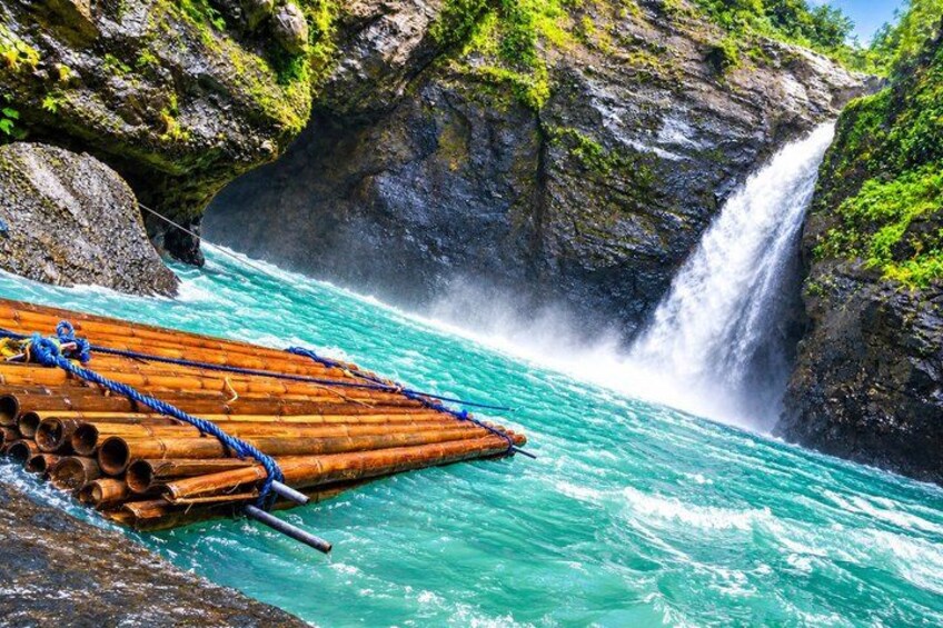 A river with a wooden raft, a waterfall, and rocky cliffs. 3