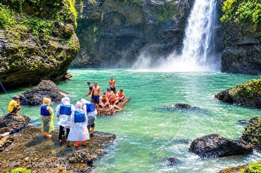 A group of people on a boat in a river with a waterfall in the background. 1