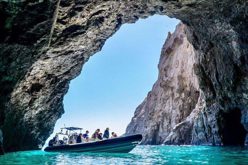 A boat with passengers in a natural rock arch formation. 3