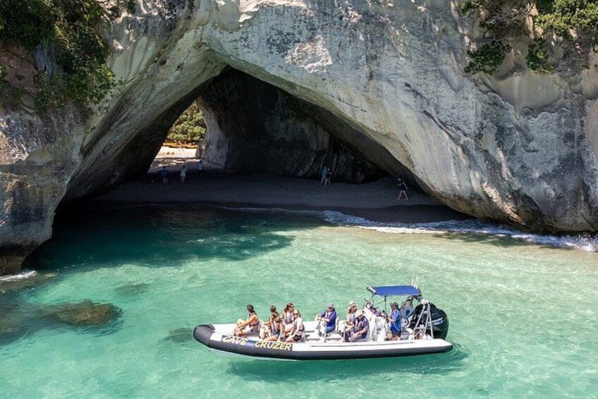 A boat with people under a large rock arch. 1