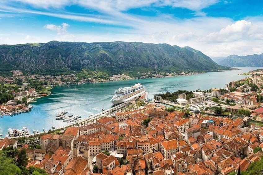 A coastal town with a cruise ship docked, mountains in the background, and a river. 3