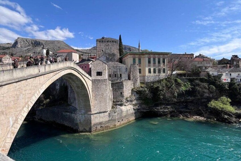 A stone bridge over a river, a historic building, and a mountainous backdrop. 3
