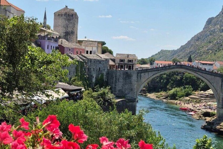 A stone bridge over a river, historic buildings, and a mountainous backdrop. 2