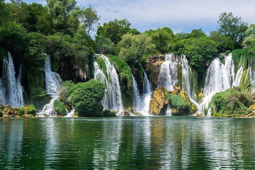A waterfall cascading over rocks into a lake surrounded by lush greenery. 3