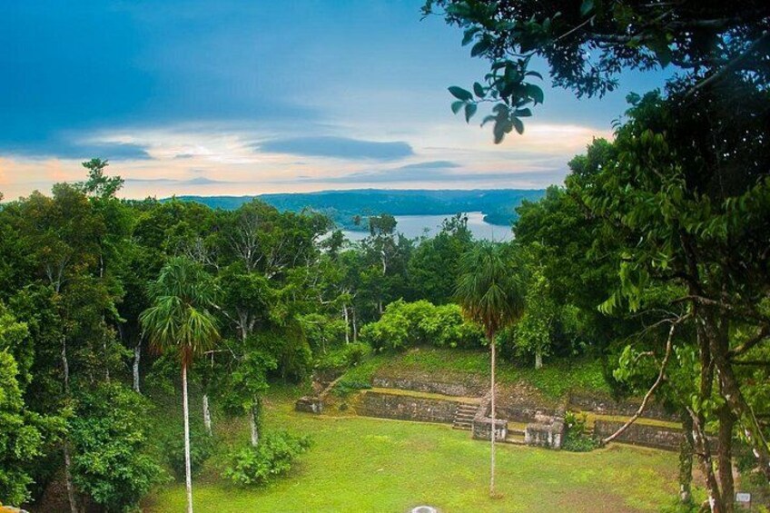 A lush green landscape with a clear view of a body of water in the distance and a stone structure in the foreground. 2