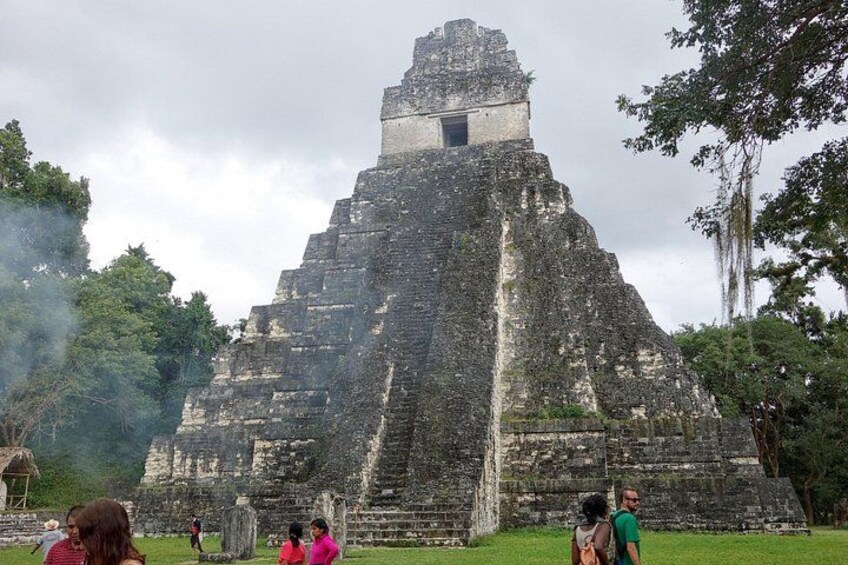 A large ancient pyramid-like structure with a small opening at the top, surrounded by lush greenery and trees. 3