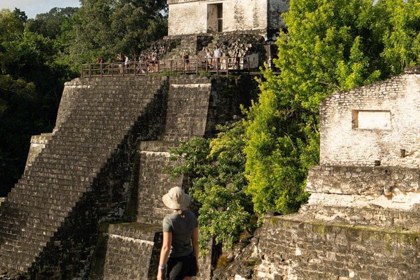 Una estructura de piedra histórica con escalones que conducen a un edificio, rodeada de vegetación. 1