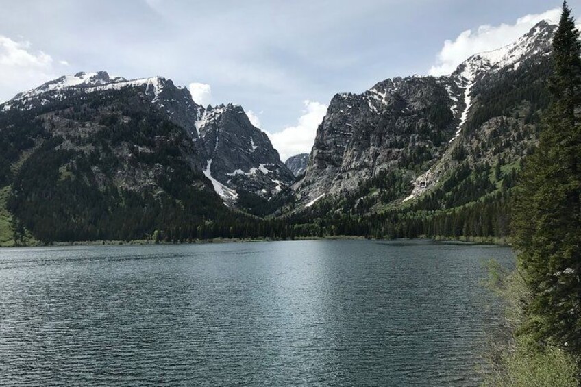 Un lago circondato da montagne con cime innevate e fitte foreste. 4