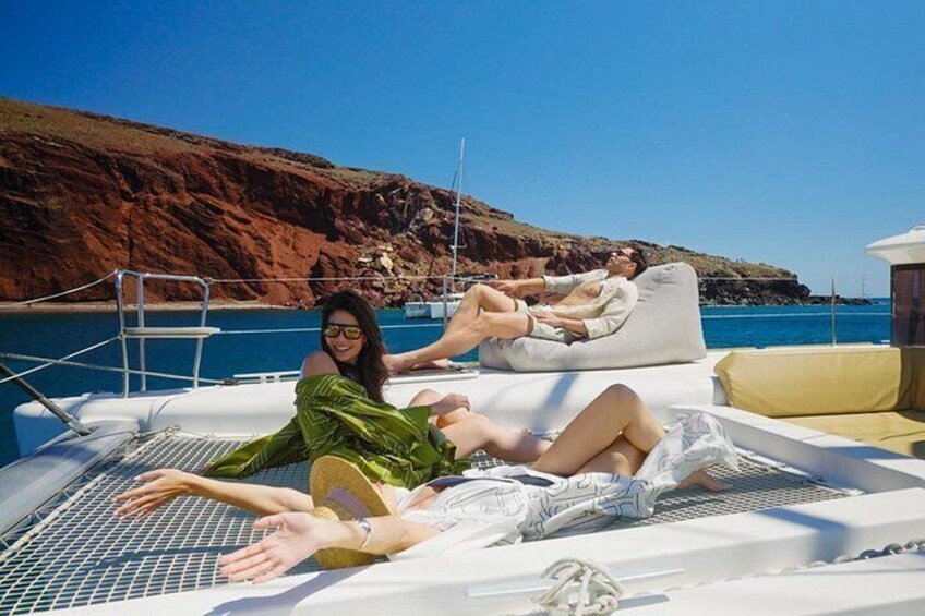 A boat with people relaxing on the deck, a rocky coastline, and calm blue waters. 4