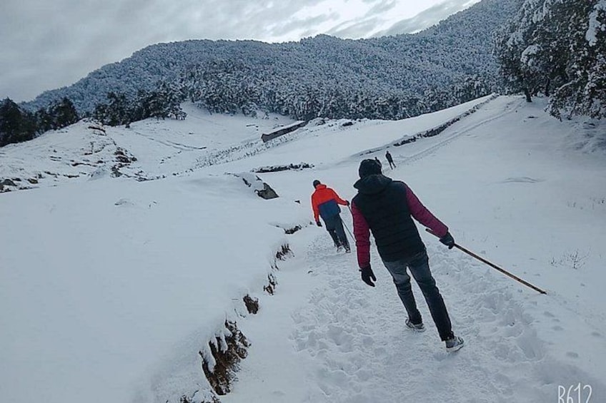 A snowy mountain landscape with skiers descending a slope. 1