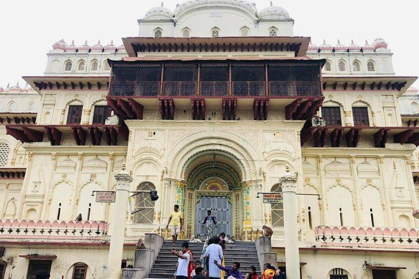 A large, ornate building with a central archway, multiple balconies, and a statue at the entrance. 2